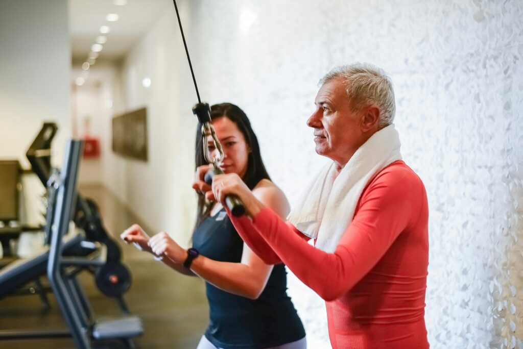 Senior man exercising in gym with personal trainer